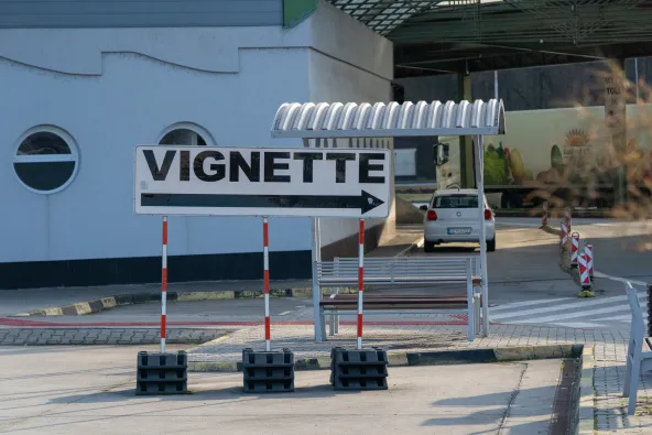 Vignette directional arrow sign at Slovakia–Czech Republic Brodské border crossing on D2 motorway, pointing drivers to vignette sales point, car and truck visible in background, February 2026